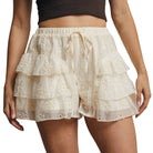 Beige lace shorts worn by a person on a white background