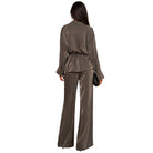 A woman shown from the back wearing a matching metallic taupe-brown two-piece set consisting of a long-sleeve belted jacket and wide-leg trousers, against a plain white background.