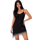 A woman modeling a black spaghetti-strap slip dress with a fringed hem against a plain white background.