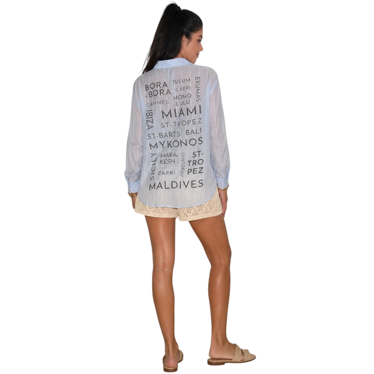 Woman wearing a light blue shirt with text on the back, standing against a white background