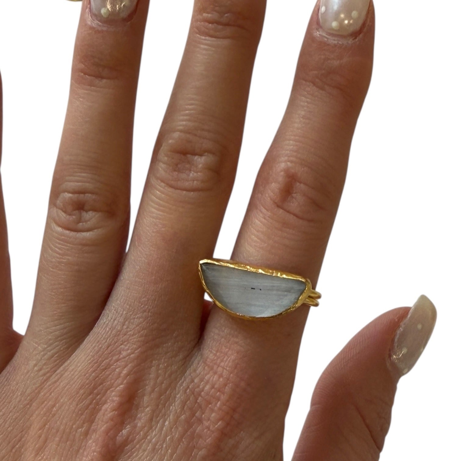 Hand wearing a gold and white ring on a plain background