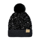 A black beanie hat covered in sequins, featuring a fluffy black pom-pom on top and a dark ribbed knit cuff with a small tan 'CC' logo patch.