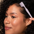 Woman with a hairbrush in her hair against a dark background