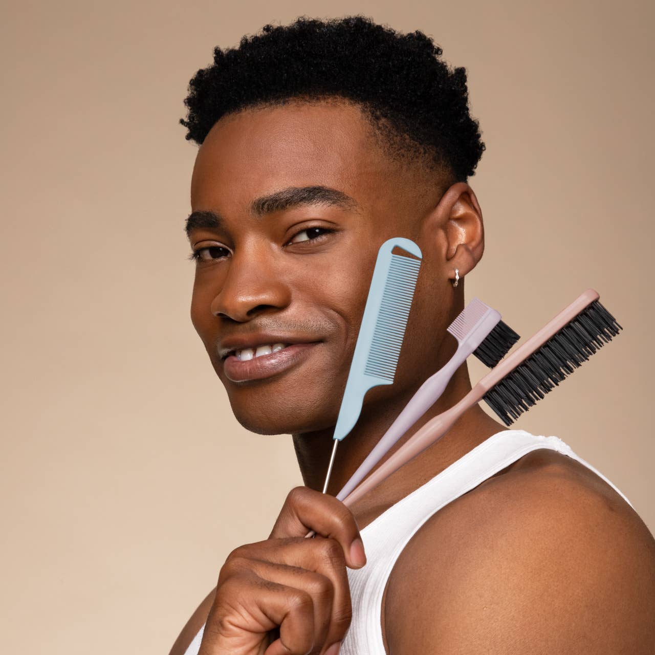 Man holding hair care tools against a beige background