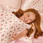 Woman lying on a bed with cherry-patterned bedding
