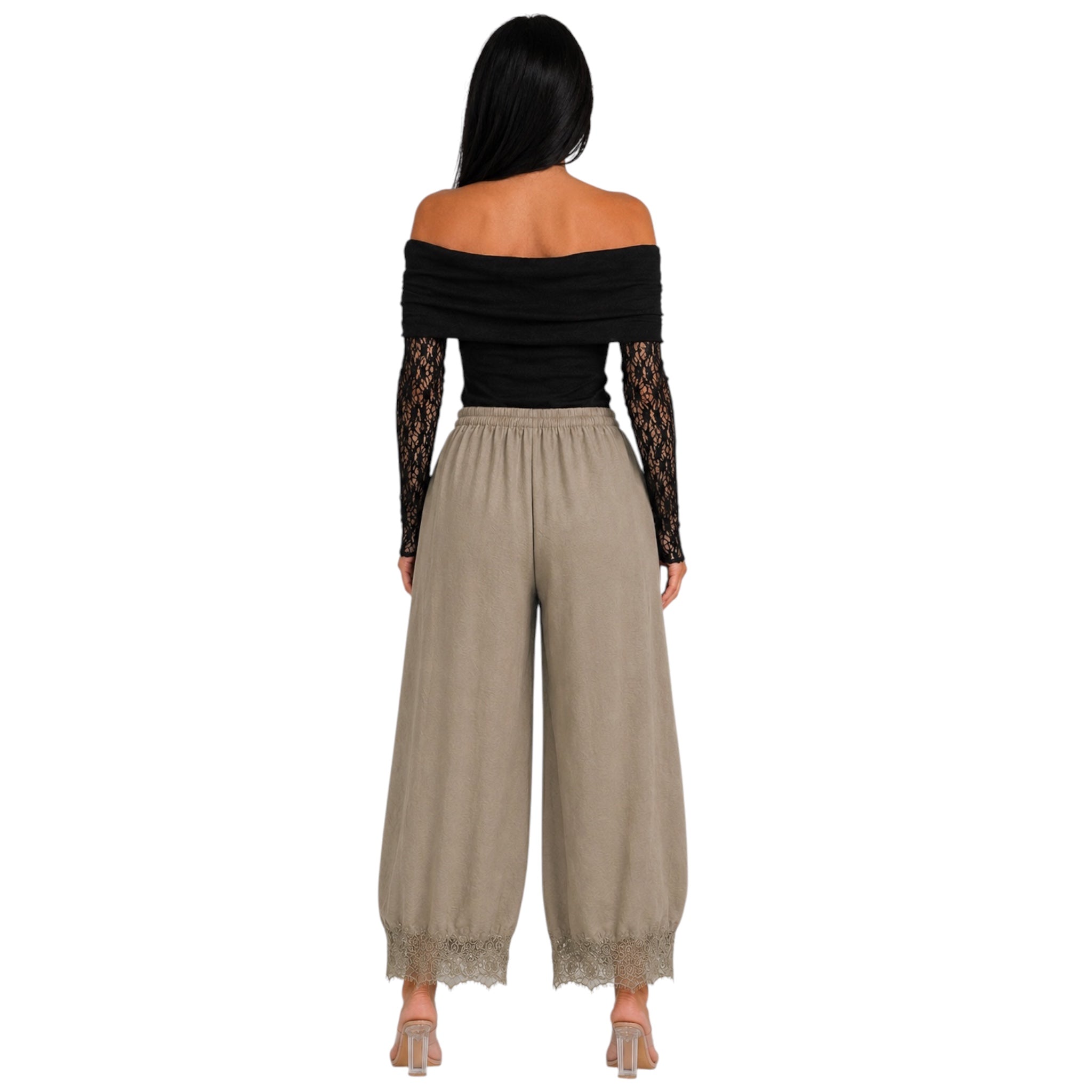 A woman shown from the back wearing a black off-the-shoulder long-sleeve top with lace sleeves and beige wide-leg pants with lace trim at the hems, against a plain white background.