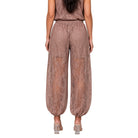 A model shown from the back wearing loose, wide-leg lace pants in a dusty rose-brown color, paired with a matching top and clear high-heeled sandals, against a plain white background.