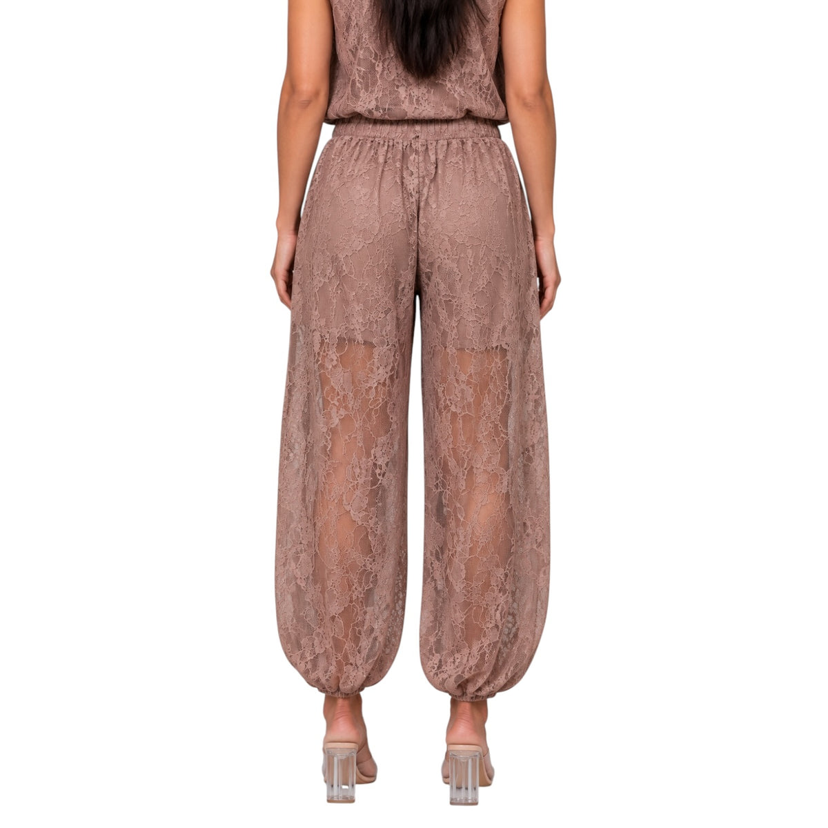 A model shown from the back wearing loose, wide-leg lace pants in a dusty rose-brown color, paired with a matching top and clear high-heeled sandals, against a plain white background.