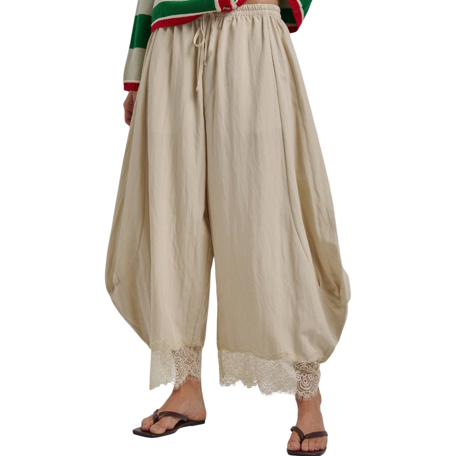 Beige wide-leg harem pants with a drawstring waist and lace trim at the hem, shown on a model wearing brown flip-flop sandals against a white background.
