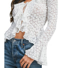 White lace top worn by a person with blue jeans on a white background