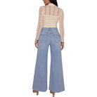 A model shown from the back wearing a cream lace long-sleeve top and light blue wide-leg denim jeans against a plain white background.
