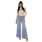 A woman modeling a cream lace long-sleeve top with light blue wide-leg denim jeans, standing against a plain white background.