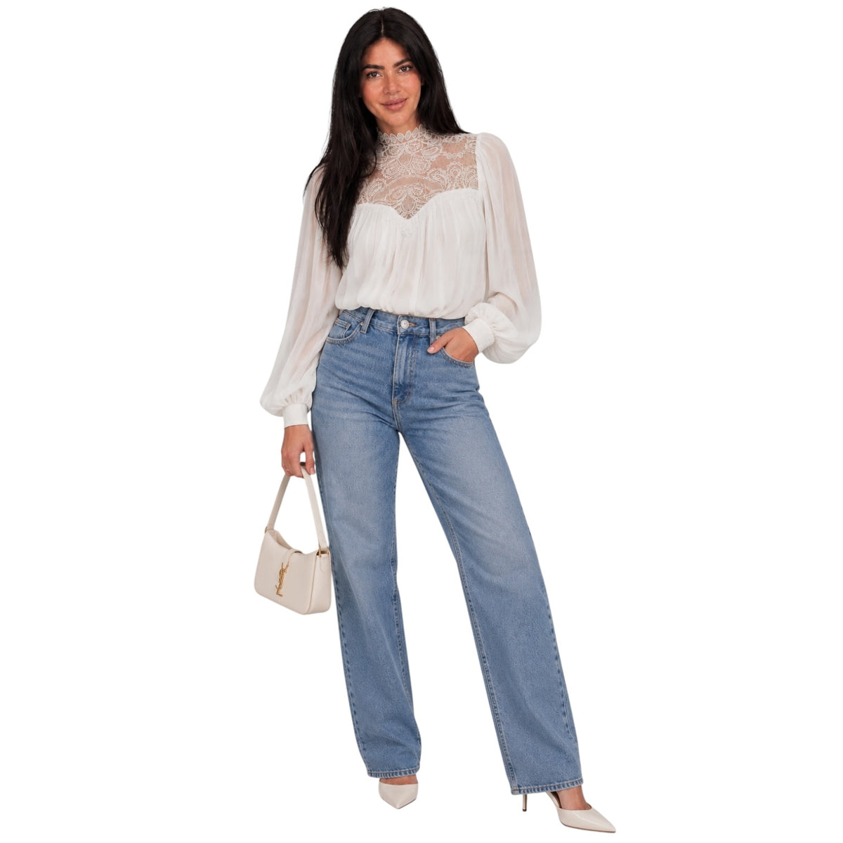 A woman modeling a white long-sleeve blouse with a sheer lace bodice and light-wash blue straight-leg jeans, holding a small cream handbag against a plain white background.