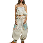 Woman wearing a floral top and wide-leg pants on a white background