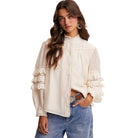 Woman wearing a white blouse with ruffled details and blue jeans on a white background