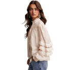 Woman wearing a beige blouse with lace details on a white background