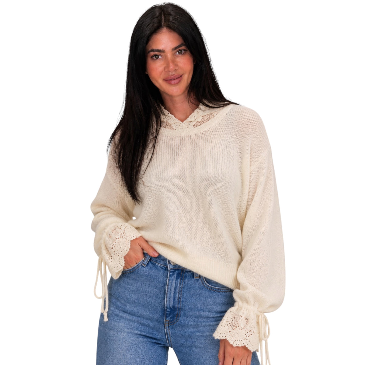 A woman modeling a cream-colored ribbed knit sweater with lace trim at the mock neck and cuffs, paired with blue jeans against a plain white background.