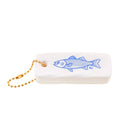 White object with blue fish design and gold chain on white background