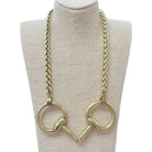 A gold-tone chain necklace with two large circular horse-bit style rings at the bottom, displayed on a beige fabric mannequin bust against a white background.