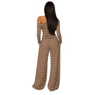 A woman viewed from the back wearing a long-sleeve off-the-shoulder jumpsuit with horizontal brown and beige stripes, set against a plain white background.