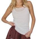 Woman wearing a white tank top and maroon skirt with lace trim on a white background