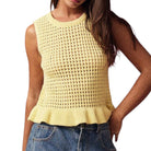 Woman wearing a yellow sleeveless knitted top with a plain background