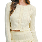 Woman wearing a lemon colored knitted set with a white background