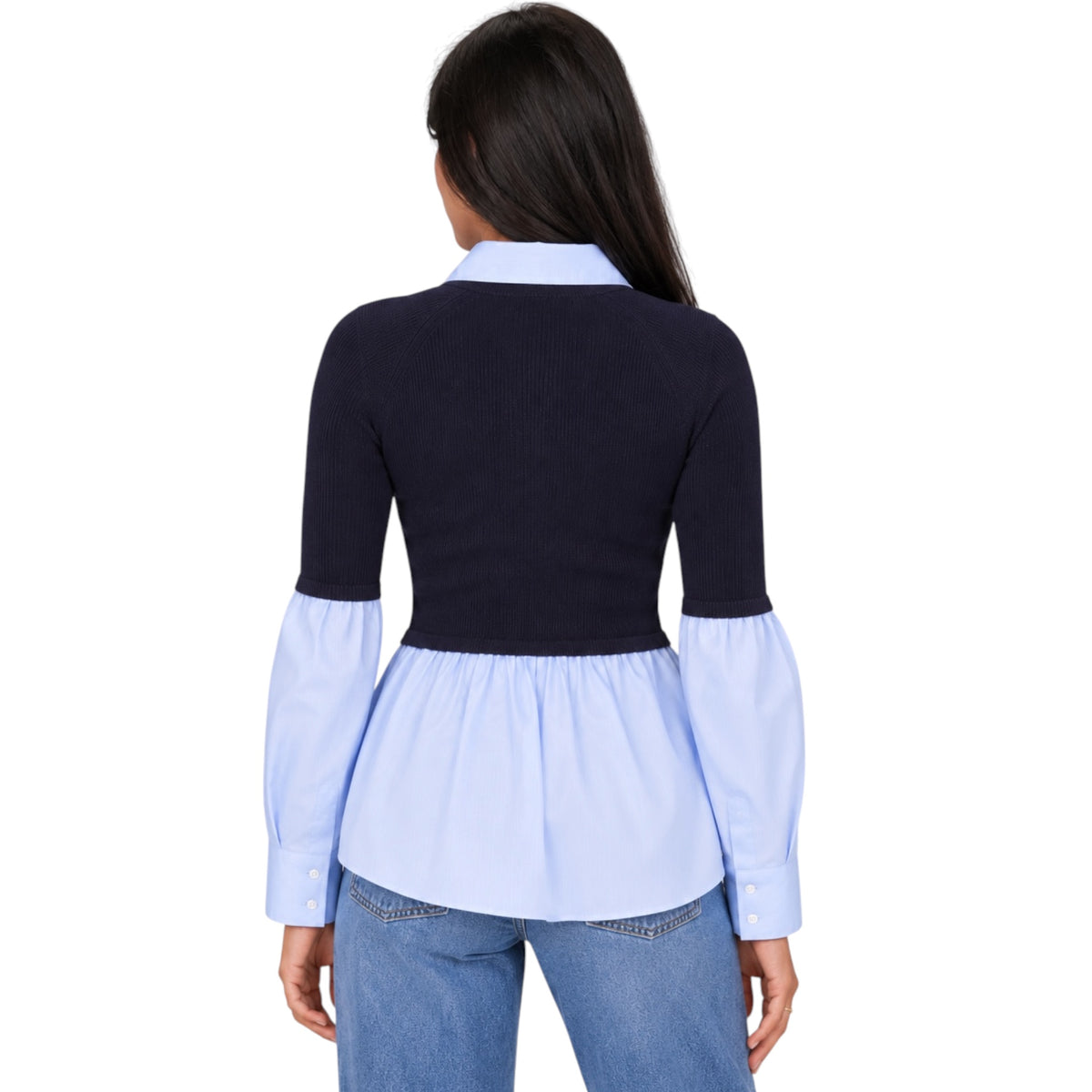 A woman shown from the back wearing a color-blocked long-sleeve blouse with a dark navy upper section, a light blue collar, and a light blue peplum hem, paired with blue jeans against a plain white background.
