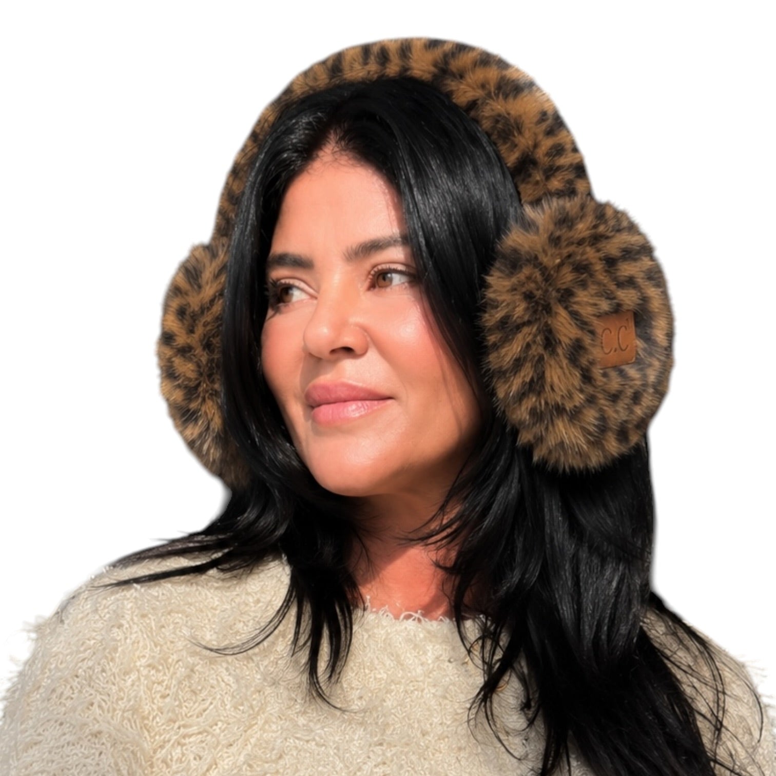 A woman wearing plush leopard-print earmuffs with a small tan brand patch on the right earcup, paired with a cream knit sweater against a plain white background.
