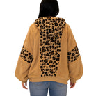 A person shown from the back wearing a tan sherpa hoodie with leopard-print panels on the hood, back, and sleeves, paired with blue jeans against a plain white background.
