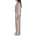 A woman shown in side profile wearing a matching two-piece tracksuit with a beige, brown, and black leopard print pattern and white vertical stripes down the sleeves and legs, set against a plain white background.