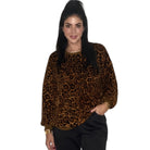 A woman modeling a brown and black leopard print long-sleeve top against a plain white background.