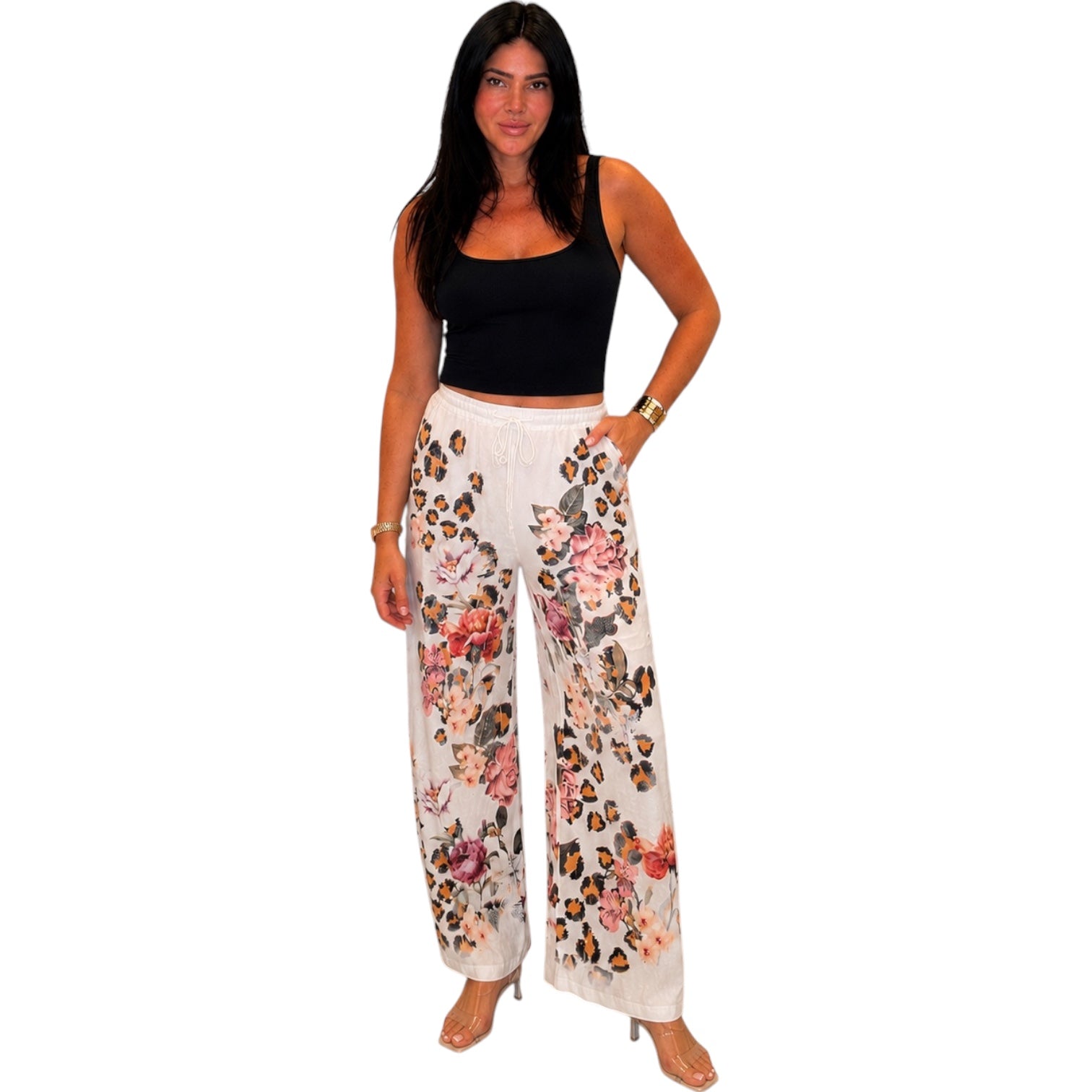 Woman wearing a black top and floral pants on a white background