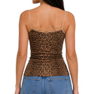 Rear view of a woman wearing a leopard-print spaghetti-strap camisole top with lace trim at the back, paired with blue jeans, against a plain white background.