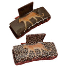 Two hair claw clips shown on a plain white background, one with a dark brown cheetah print and the other with a leopard print, both featuring textured sides and reddish-brown inner clasp areas.