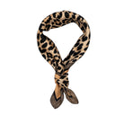 A leopard print silk scarf with a tan and black pattern, tied in a loop with the ends knotted, displayed on a clean white background.