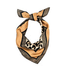 A square silk scarf styled in a knot, featuring a dual-pattern design: one side has a solid tan/beige border with black glitter-like speckles, and the other side features a black and beige leopard print. The center knot area is a solid tan/beige.