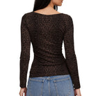 A woman shown from the back wearing a fitted long-sleeve leopard-print top in dark brown and black, paired with light blue jeans, against a plain white background.