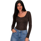 A woman modeling a brown and black leopard print long-sleeve scoop-neck top paired with blue jeans, set against a plain white background.