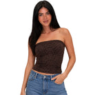 A woman modeling a brown and black leopard print strapless tube top paired with blue jeans, set against a plain white background.