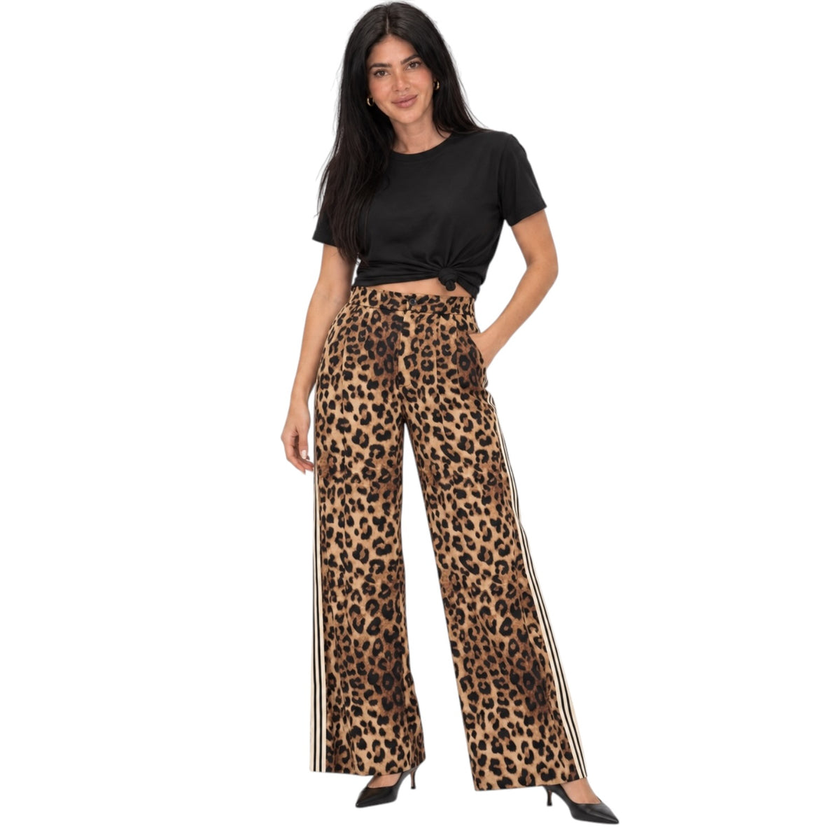 A woman modeling high-waisted, wide-leg leopard print pants with black side stripes, paired with a black cropped t-shirt and black heels, against a plain white background.