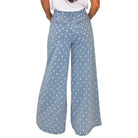 woman wearing light denim polka dot wide leg pants on white background
