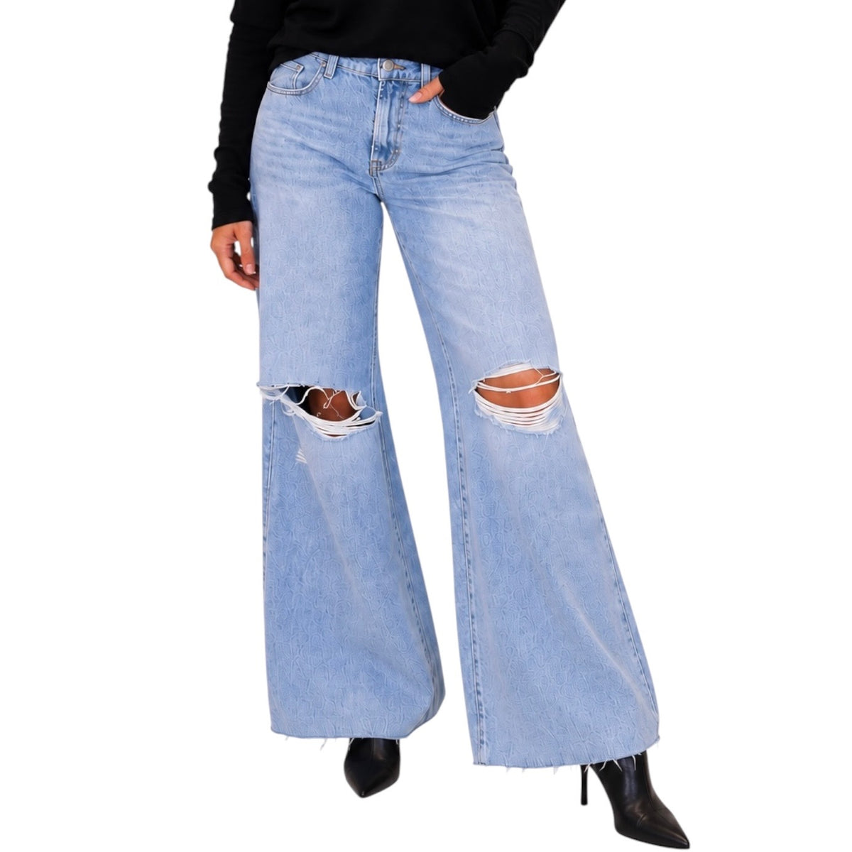 Light wash blue wide-leg distressed jeans with ripped knees, shown on a model wearing a black top and black pointed-toe heels against a white background.