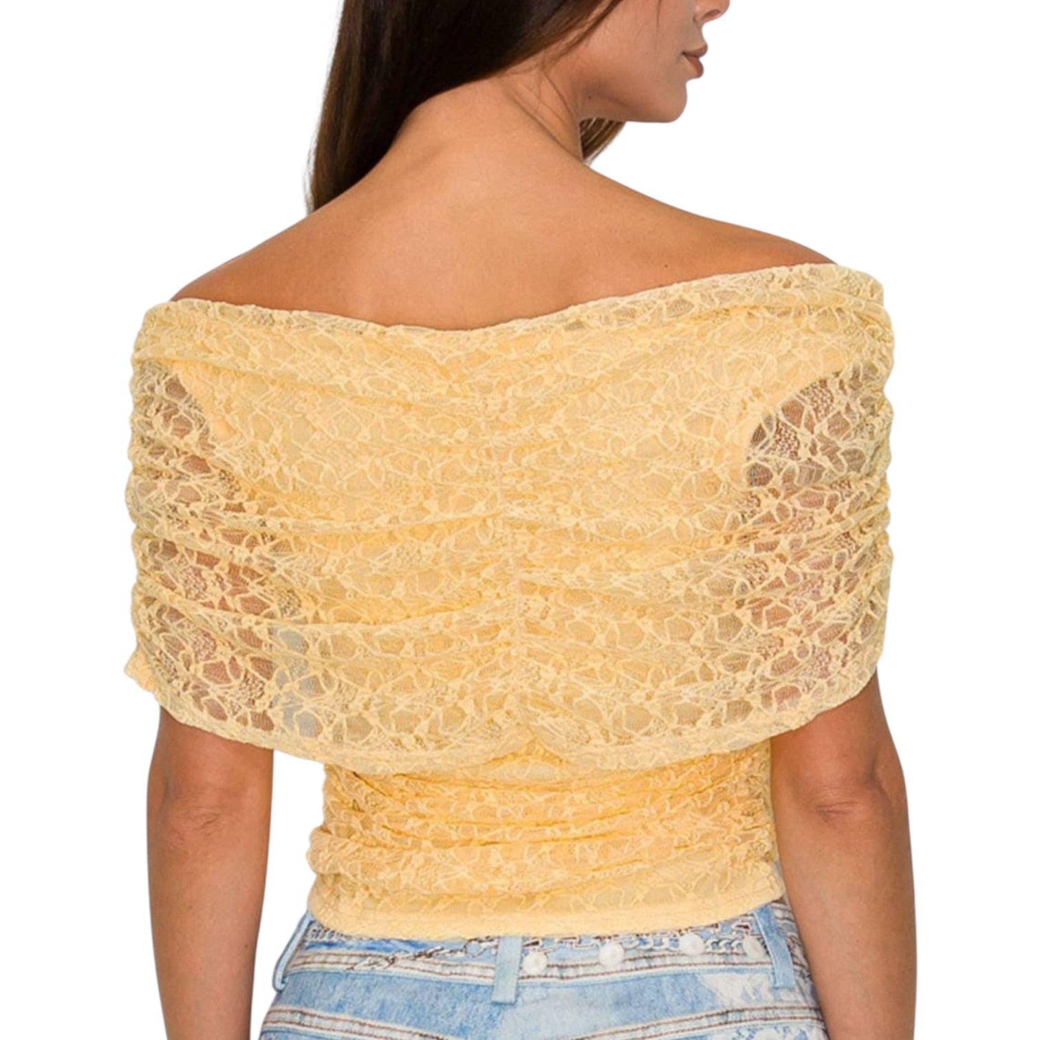 Woman wearing a yellow lace top with denim shorts on a white background