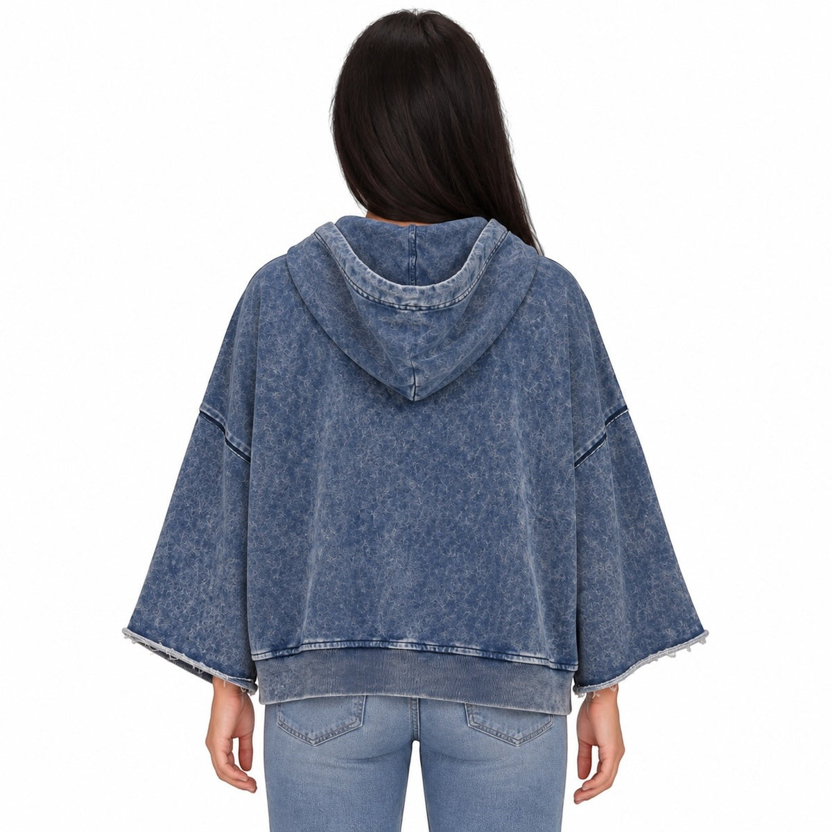 A woman viewed from the back wearing a faded blue hooded sweatshirt with wide drop-shoulder sleeves and light-wash jeans, against a plain white background.