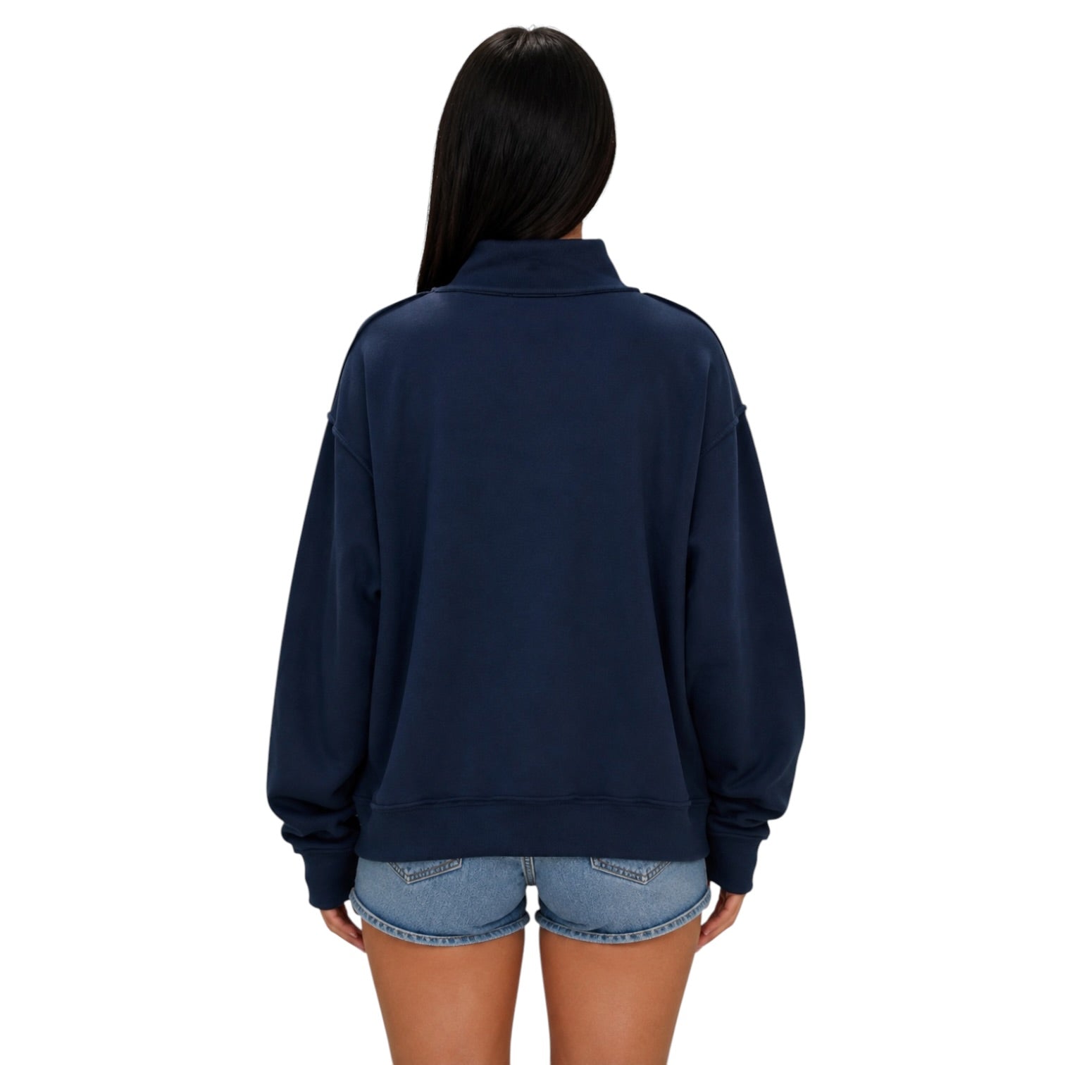 A woman viewed from the back wearing an oversized navy blue sweatshirt and light blue denim shorts against a plain white background.