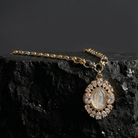 Gold necklace with a pendant on a dark stone surface