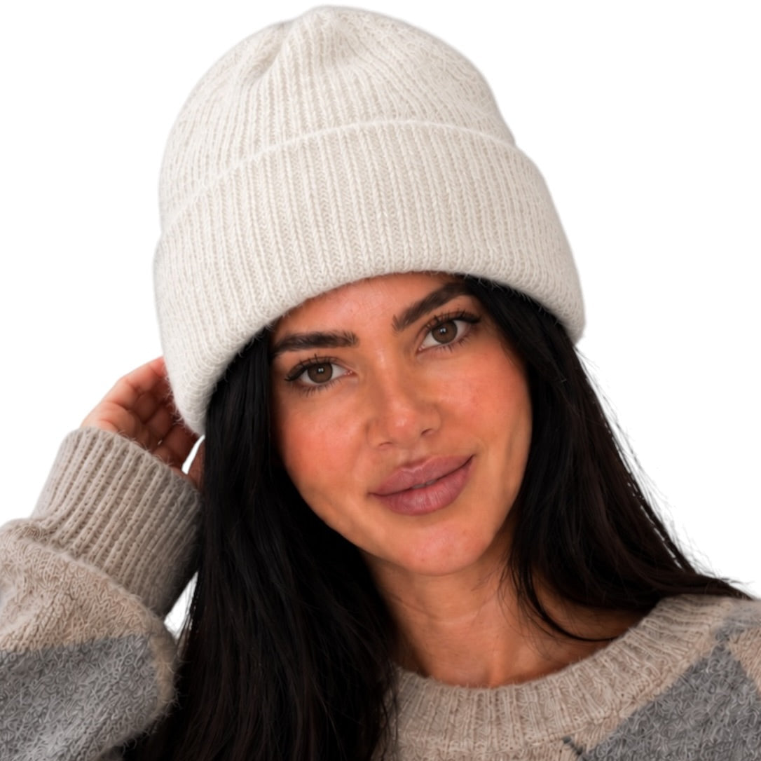 A woman wearing a cream ribbed knit beanie and a gray and beige argyle sweater, shown against a plain white background.