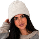 A woman wearing a cream ribbed knit beanie and a gray and beige argyle sweater, shown against a plain white background.