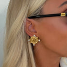 Gold earring with pearls worn by a person with blonde hair.